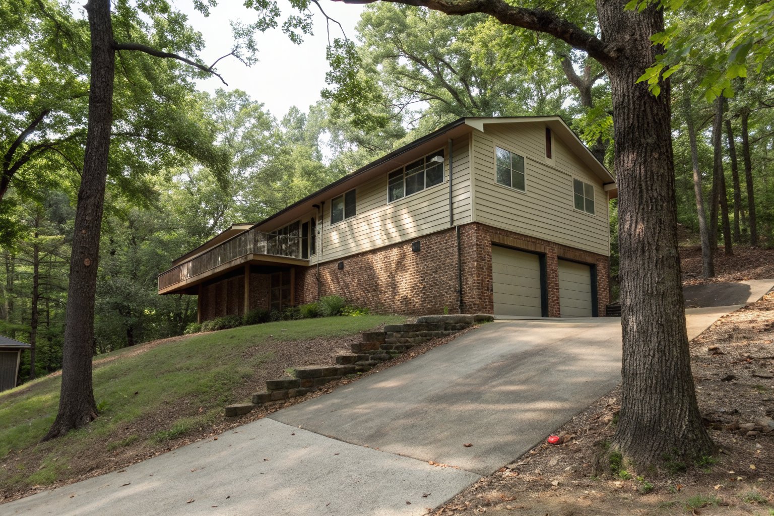 1970s split-level house with a brick lower level and wood siding above, on a wooded slope